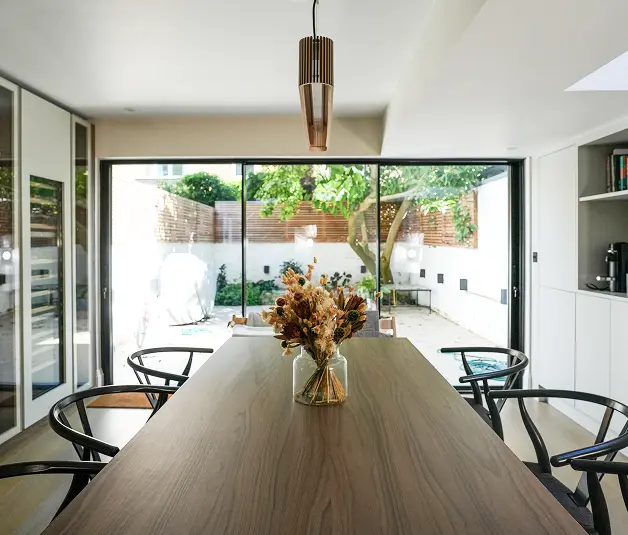 Builders London built a modern Fulham kitchen and dining area with wooden finishes and large glass doors.
