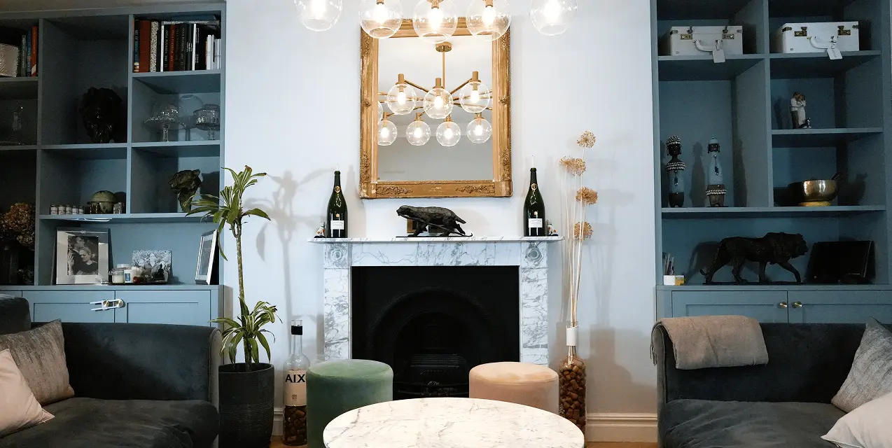 Terrace house renovation in Chelsea with chandelier, sofas, and marble fireplace.