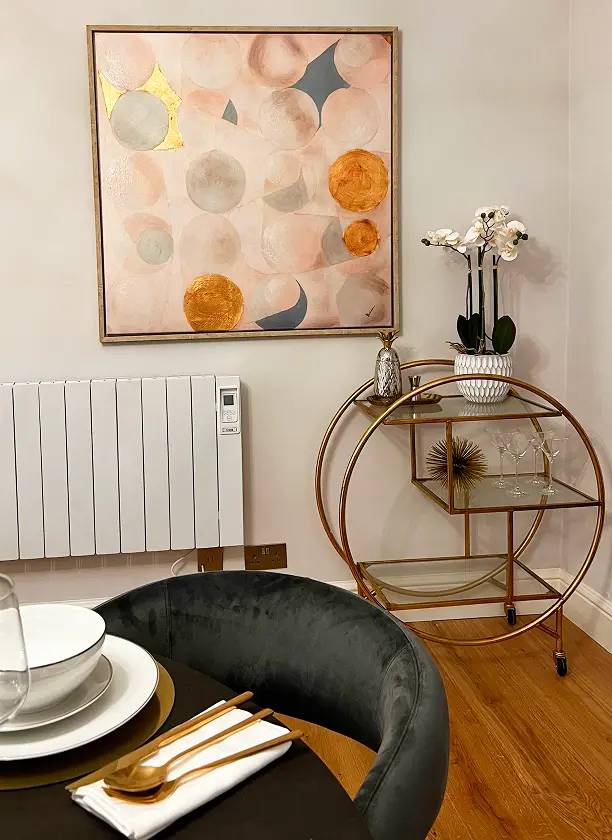 Modern apartment renovation in Kensington featuring elegant dining nook with abstract wall art and gold bar cart.