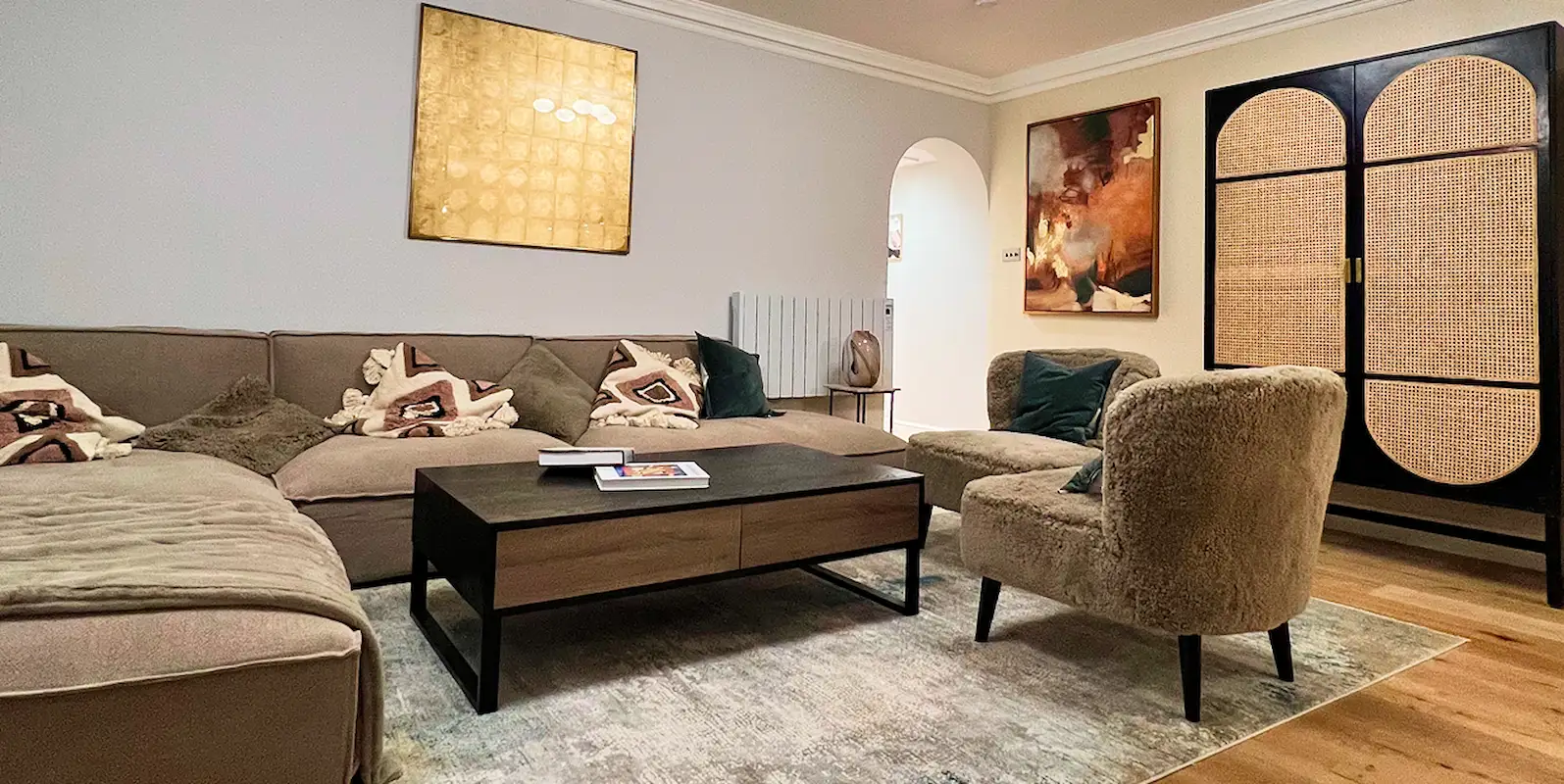 Renovated Kensington apartment living room with armchairs, cabinet, and artwork.