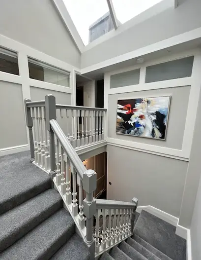Renovation projects loft conversion with modern staircase, skylight, and refined grey interior.