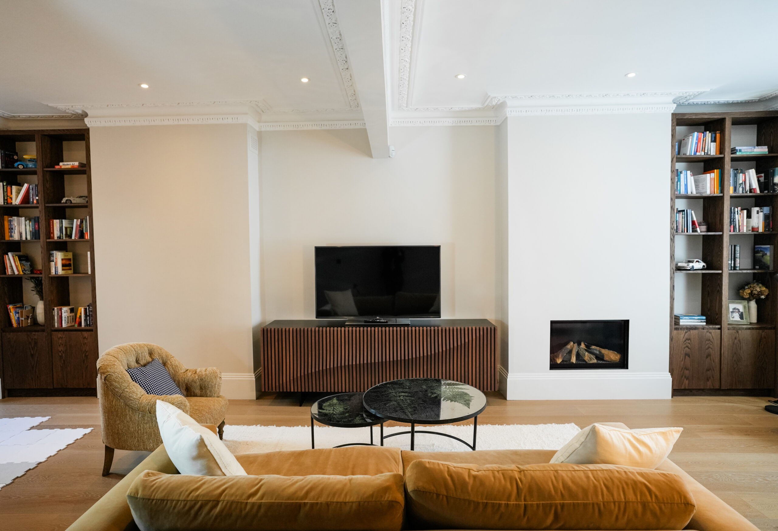 Step by step house renovation UK finished living room with fireplace, fitted shelving and timber floor