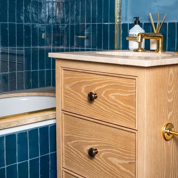 Bathroom renovation London vanity close-up with blue tiles and brass fittings.