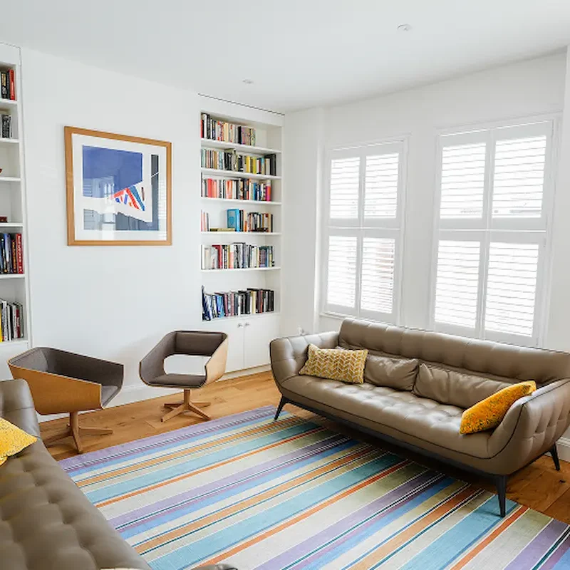 Text: Builders in Chelsea delivering modern living room refurbishment with bespoke shelving and luxury finishes.