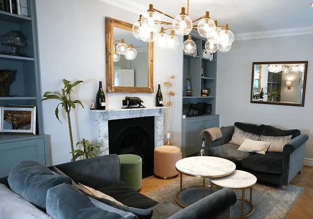 Terrace house renovation in Chelsea with chandelier, sofas, and marble fireplace.