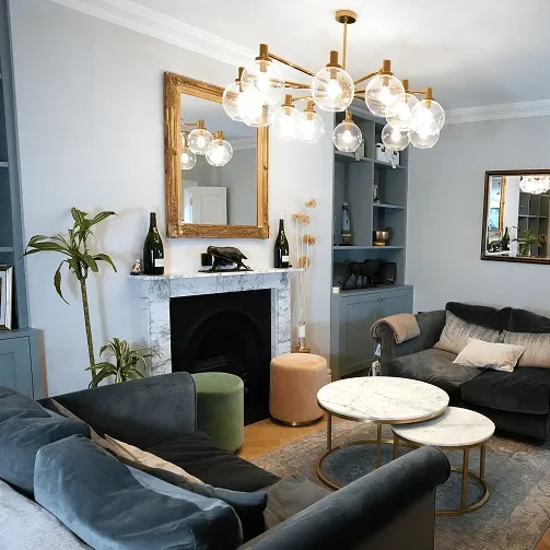 Terrace house renovation in Chelsea with chandelier, sofas, and marble fireplace.
