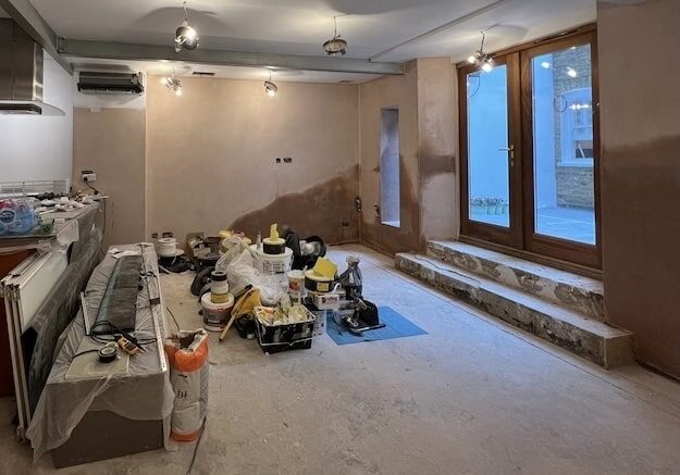 Damp proofing London – lower-ground room before treatment with visible damp staining on walls and ongoing renovation works.