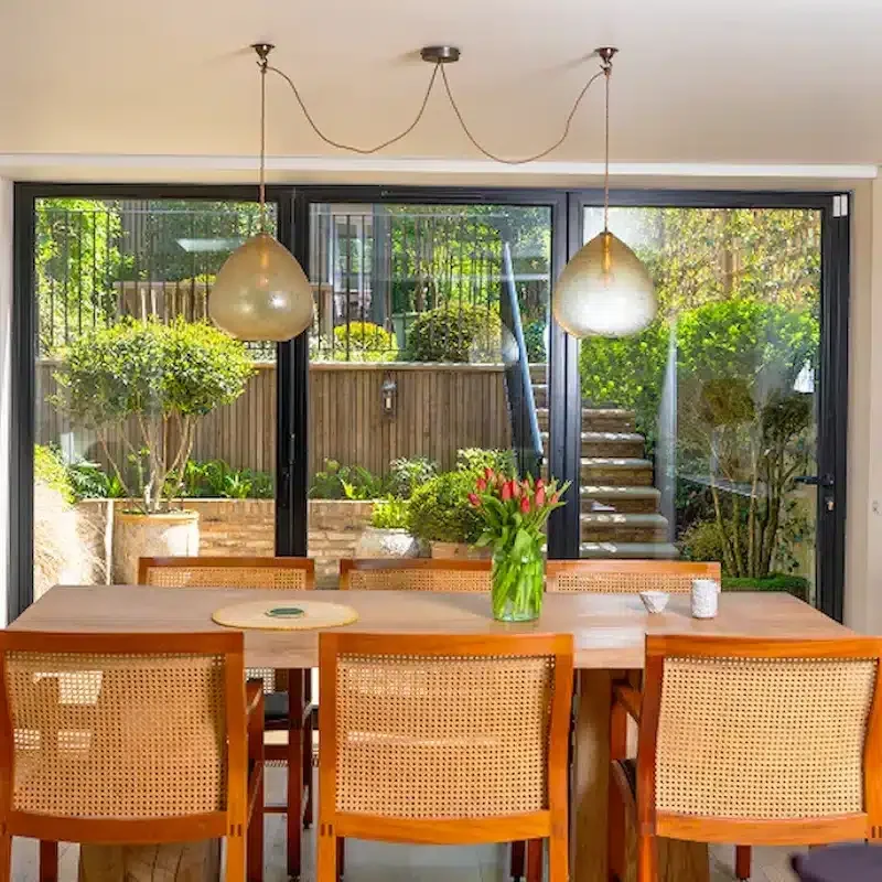 Dining area in a renovated Notting Hill home with full-width glazing and views onto the garden.