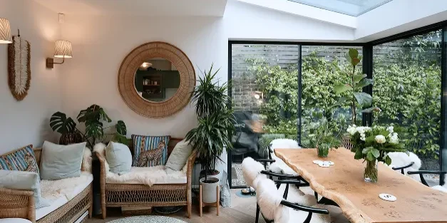 House extensions London with bright garden room featuring wicker seating and glass roof.