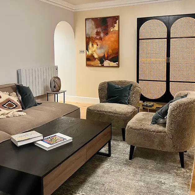 Renovated Kensington apartment living room with armchairs, cabinet, and artwork.