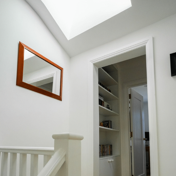 Light-filled hallway from a Loft Conversion London project, featuring skylight and built-in shelving.
