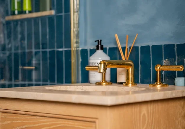 Renovated Victorian house bathroom in Notting Hill with brass taps and blue tiled wall.