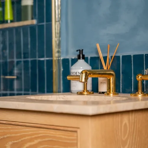 Renovated Victorian house bathroom in Notting Hill with brass taps and blue tiled wall.